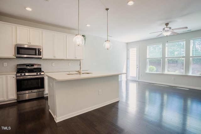 kitchen with decorative backsplash, dark wood-style floors, light countertops, a sink, and appliances with stainless steel finishes