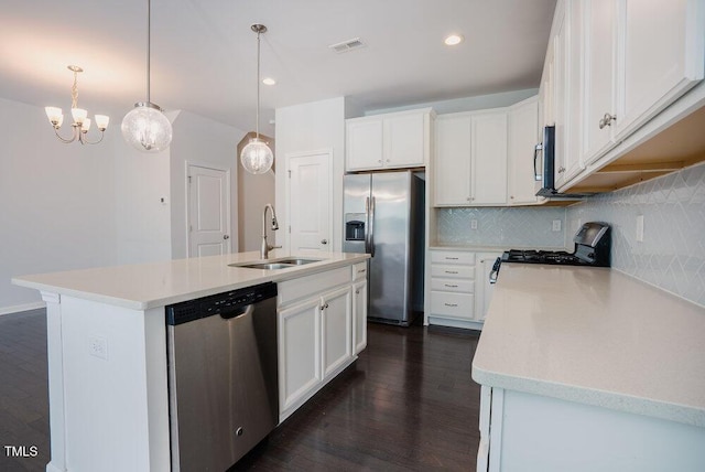 kitchen with dark wood-style flooring, a sink, stainless steel appliances, tasteful backsplash, and visible vents