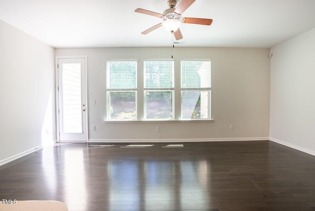 spare room featuring a ceiling fan, baseboards, and dark wood-type flooring