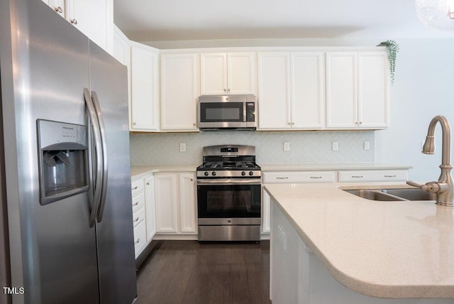 kitchen featuring backsplash, dark wood-style flooring, appliances with stainless steel finishes, a sink, and white cabinetry