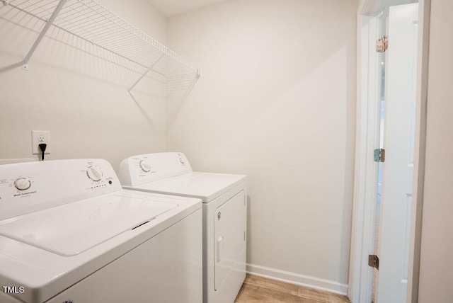 washroom with baseboards, laundry area, washer and clothes dryer, and light wood-style floors
