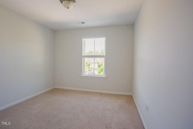 spare room featuring baseboards, light carpet, and visible vents