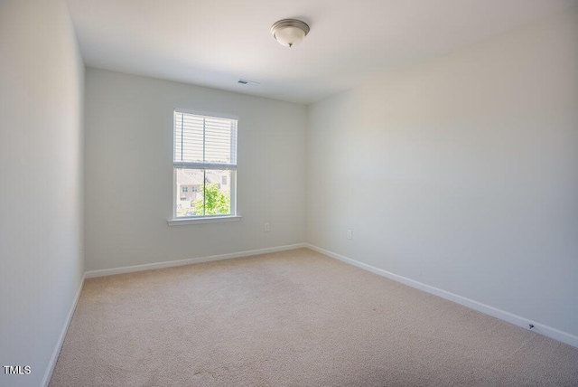 spare room featuring baseboards, visible vents, and light colored carpet