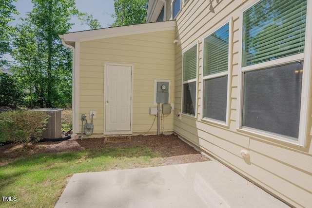view of exterior entry with central air condition unit and a patio