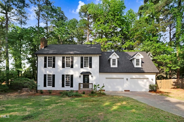 colonial-style house with a chimney, fence, a front lawn, concrete driveway, and an attached garage