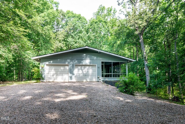 5213 Tomahawk Trl, Raleigh, NC 27610 - view of front facade with a garage, a sunroom, driveway, and a forest view