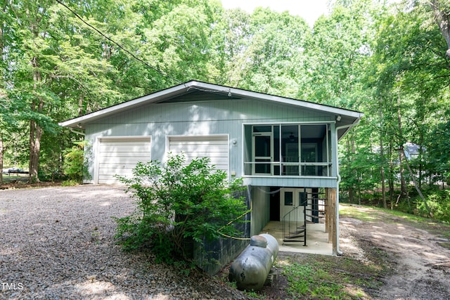 5213 Tomahawk Trl, Raleigh, NC 27610 - view of front of home featuring a detached garage, a sunroom, driveway, and a view of trees