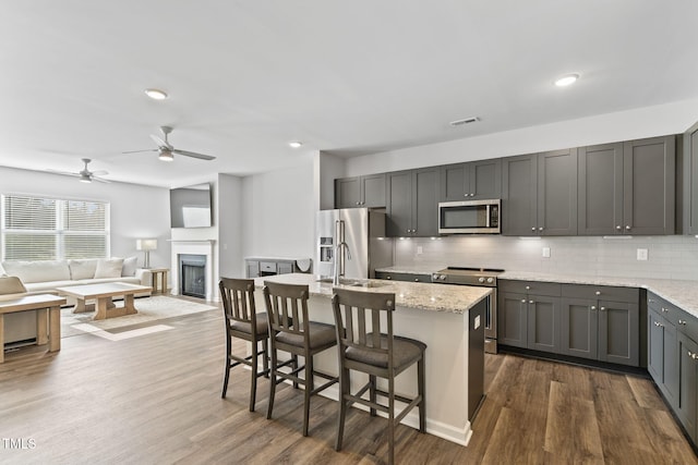 kitchen featuring light stone countertops, stainless steel appliances, tasteful backsplash, and open floor plan