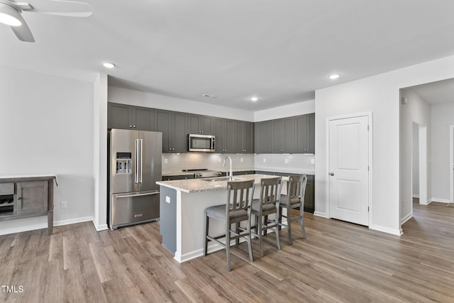 kitchen featuring light wood-style flooring, recessed lighting, a sink, backsplash, and appliances with stainless steel finishes