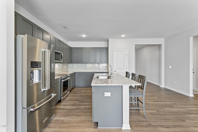 kitchen with dark wood-style flooring, premium appliances, a sink, and a kitchen bar