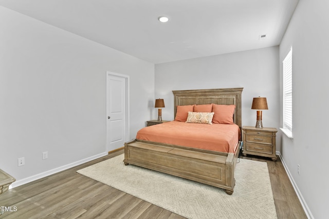 bedroom with baseboards, visible vents, and wood finished floors