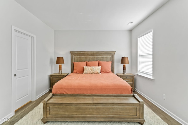 bedroom featuring baseboards, visible vents, and wood finished floors