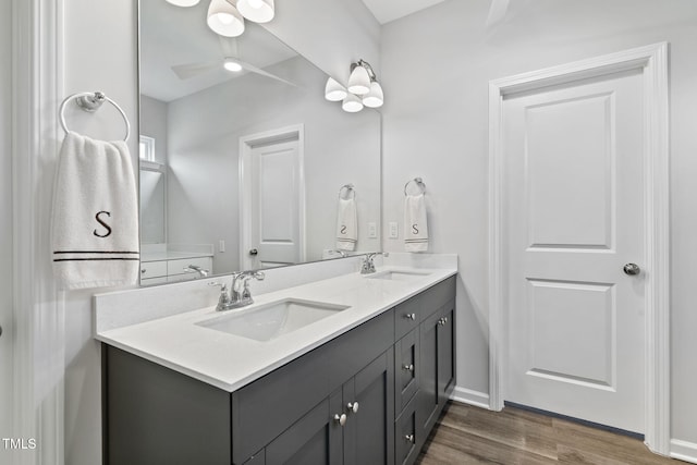 bathroom featuring ceiling fan, double vanity, a sink, and wood finished floors