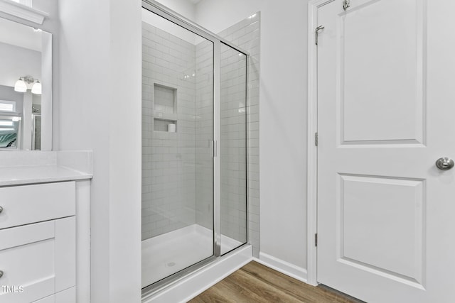 full bathroom with a shower stall, baseboards, vanity, and wood finished floors