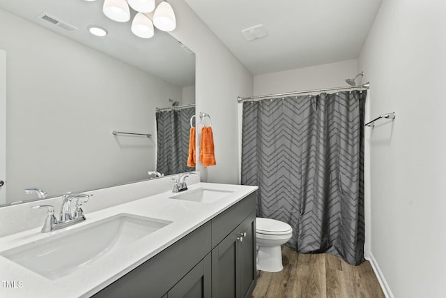 full bath with a sink, toilet, visible vents, and wood finished floors