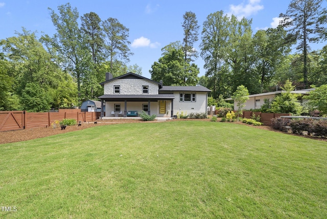 rear view of house with covered porch, a chimney, a yard, and fence private yard