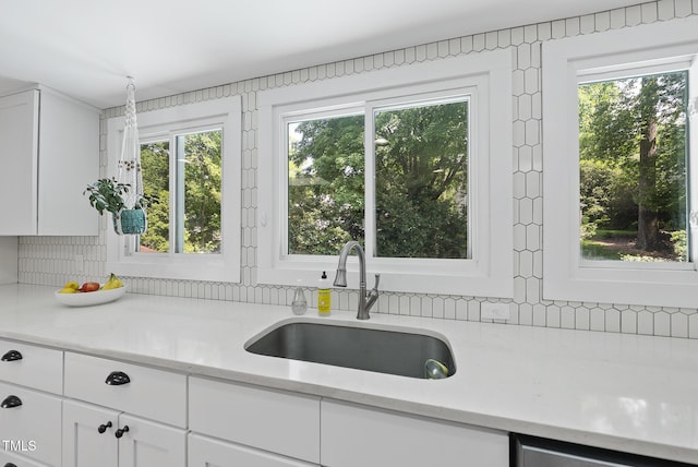 kitchen featuring backsplash, white cabinets, and a sink