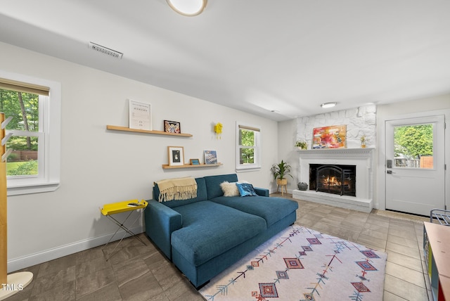 living area featuring a large fireplace, baseboards, and visible vents