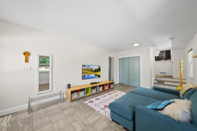 living room featuring baseboards, stairs, and visible vents