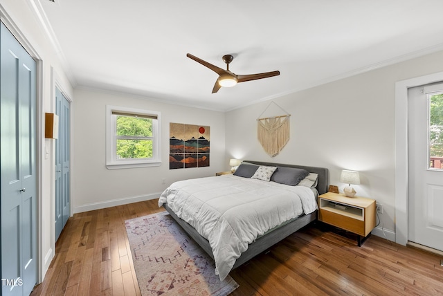 bedroom with baseboards, ornamental molding, wood-type flooring, and a ceiling fan