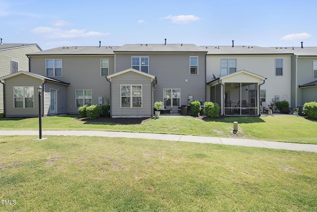 rear view of property with a lawn and a sunroom