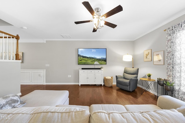 living area featuring crown molding, ceiling fan, baseboards, and wood finished floors