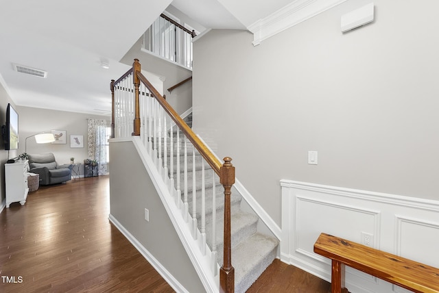 stairs with ornamental molding, wood finished floors, and visible vents