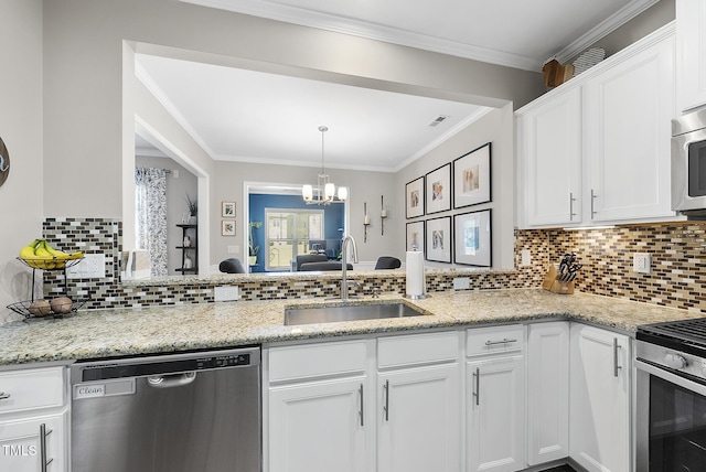 kitchen featuring white cabinets, appliances with stainless steel finishes, an inviting chandelier, a sink, and backsplash