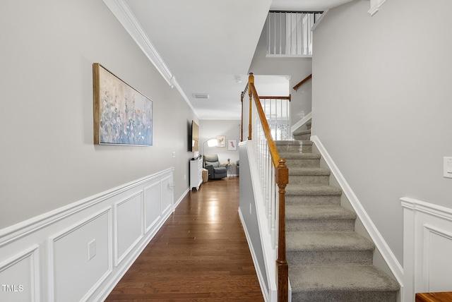 stairs featuring crown molding, wood finished floors, and visible vents
