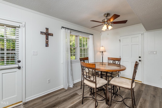 dining room with a textured ceiling, ornamental molding, and wood finished floors