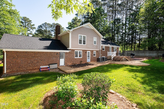 rear view of property featuring fence, brick siding, a chimney, a patio area, and a yard