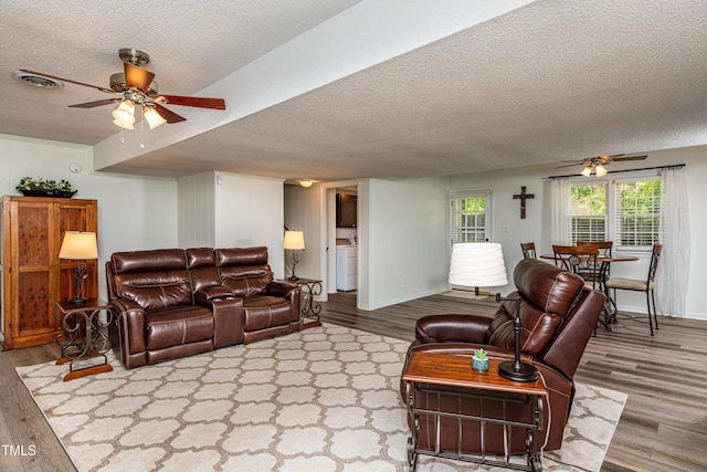 living room featuring washer / clothes dryer, a ceiling fan, a textured ceiling, and wood finished floors