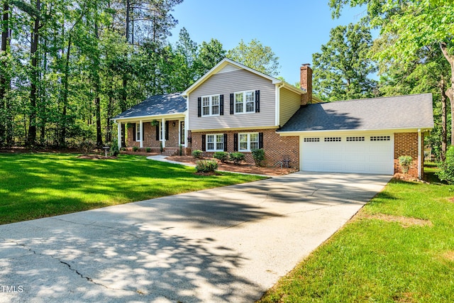 tri-level home featuring a front yard, a chimney, brick siding, an attached garage, and driveway