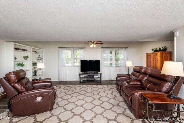 living area featuring a ceiling fan and a textured ceiling