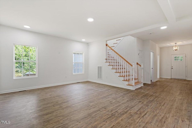 unfurnished living room with stairway, a healthy amount of sunlight, and visible vents