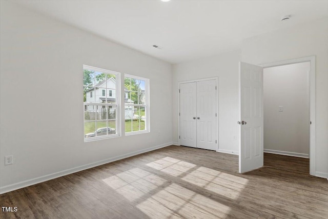 unfurnished bedroom with baseboards, visible vents, and wood finished floors