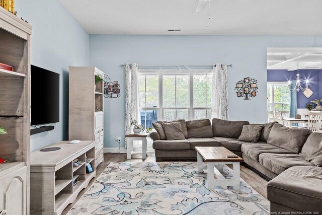 living room with visible vents, beam ceiling, wood finished floors, a notable chandelier, and coffered ceiling