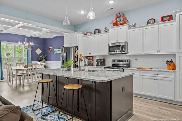 kitchen with stainless steel appliances, white cabinets, an inviting chandelier, coffered ceiling, and light wood-style flooring