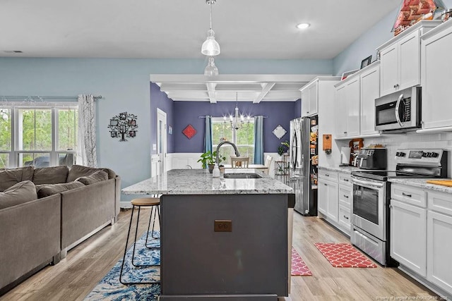 kitchen featuring open floor plan, white cabinetry, a sink, coffered ceiling, and appliances with stainless steel finishes
