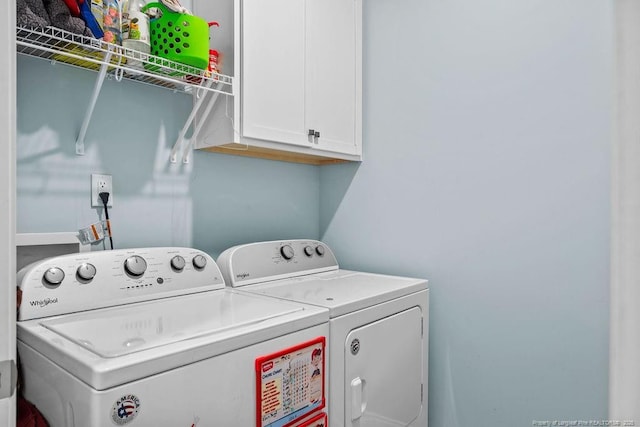 clothes washing area featuring separate washer and dryer and cabinet space