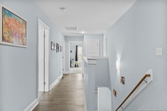hall with baseboards, an upstairs landing, visible vents, and dark wood-type flooring