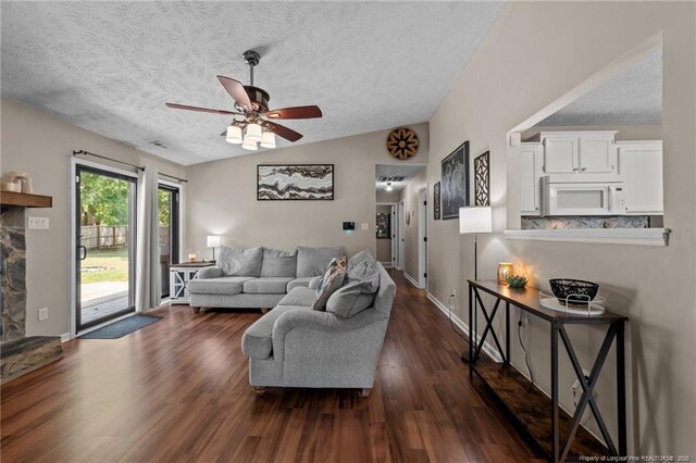 living area featuring a ceiling fan, a textured ceiling, visible vents, vaulted ceiling, and dark wood finished floors