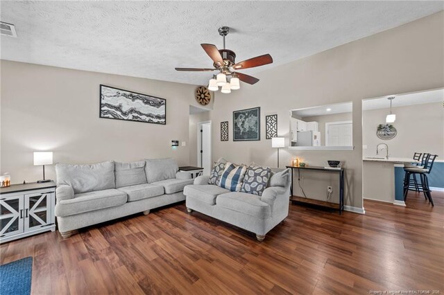 living room featuring baseboards, a textured ceiling, ceiling fan, and wood finished floors