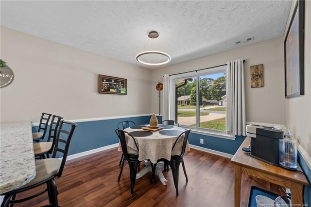 dining room with a textured ceiling, baseboards, visible vents, and dark wood-type flooring
