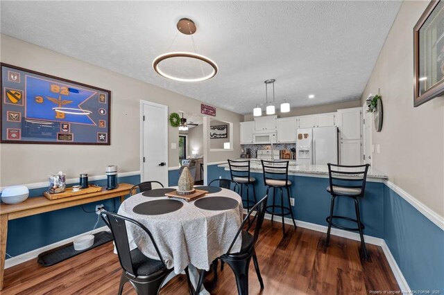dining area with baseboards, a textured ceiling, and dark wood-style floors
