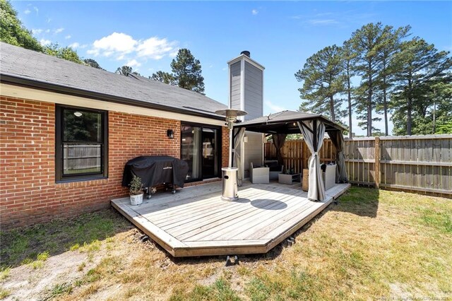 exterior space featuring fence, a gazebo, a chimney, and brick siding