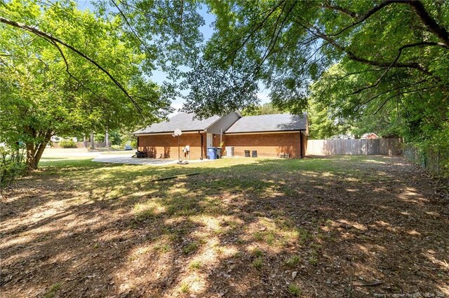 rear view of house featuring brick siding and fence