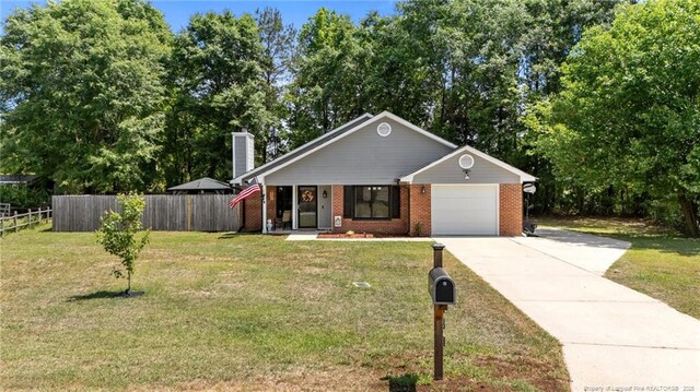view of front of house featuring a front lawn, fence, a chimney, concrete driveway, and an attached garage