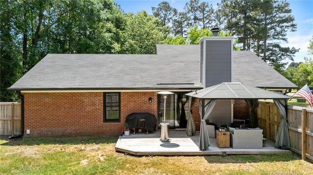 rear view of house with a gazebo, a fenced backyard, a wooden deck, and a yard
