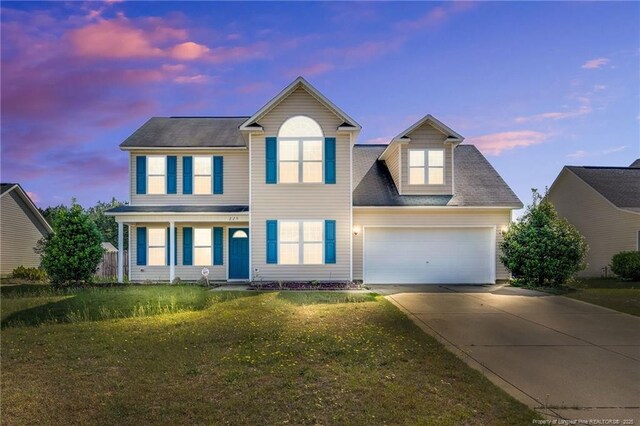 traditional-style home with an attached garage, a lawn, and driveway